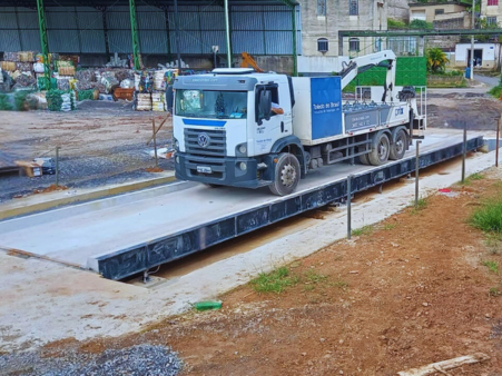Caminhão sobre balança rodoviária em área industrial, ilustrando os serviços da Potência Estrutural em instalação, manutenção e calibração de balanças com alta precisão e eficiência logística.